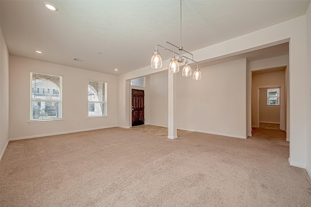 empty room featuring recessed lighting, light colored carpet, a textured ceiling, and baseboards