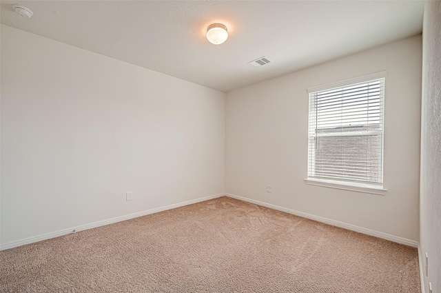 spare room with light carpet, visible vents, and baseboards