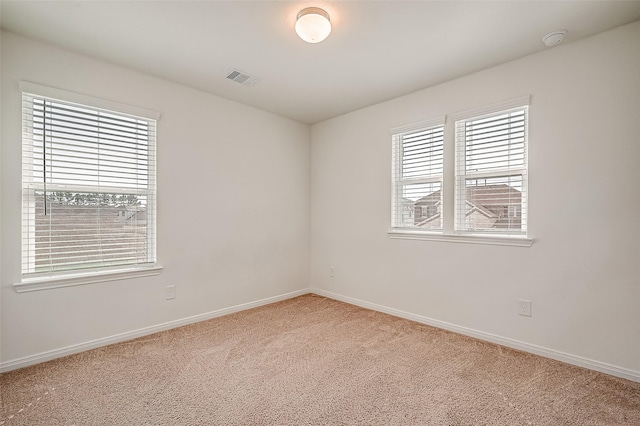 empty room featuring baseboards, visible vents, and light colored carpet