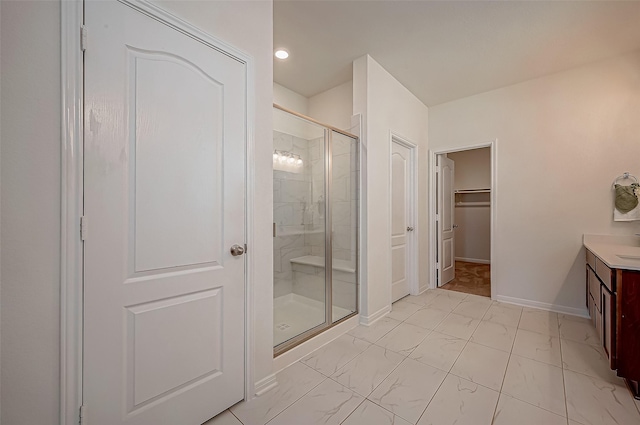 bathroom featuring vanity, baseboards, marble finish floor, a spacious closet, and a shower stall