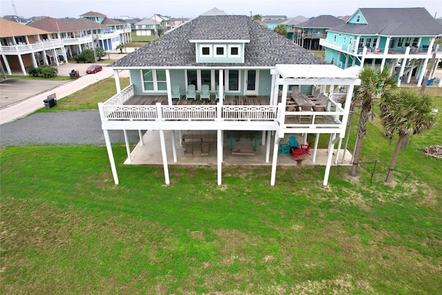 rear view of house featuring a wooden deck, a pergola, a lawn, and a patio area