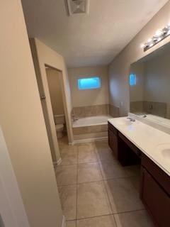 bathroom featuring vanity, a bath, tile patterned floors, and toilet