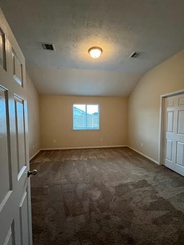 unfurnished room with dark carpet and vaulted ceiling