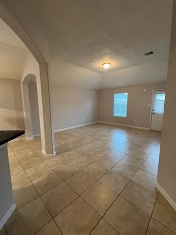 spare room featuring vaulted ceiling and light tile patterned floors