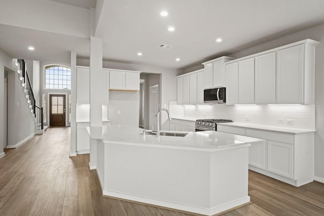 kitchen featuring white cabinetry, sink, and a center island with sink