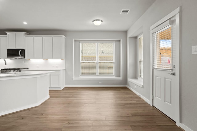 kitchen featuring white cabinetry, decorative backsplash, plenty of natural light, and light wood-type flooring