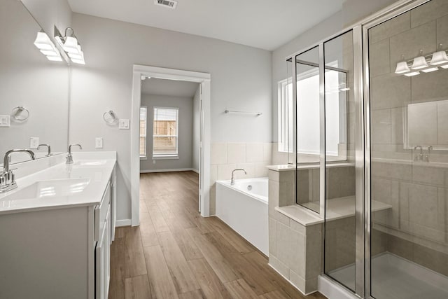 bathroom with hardwood / wood-style flooring, vanity, and plus walk in shower