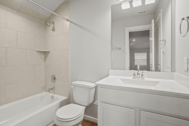 full bathroom with tiled shower / bath, vanity, and toilet