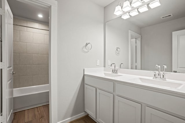 bathroom featuring hardwood / wood-style flooring, tiled shower / bath, and vanity