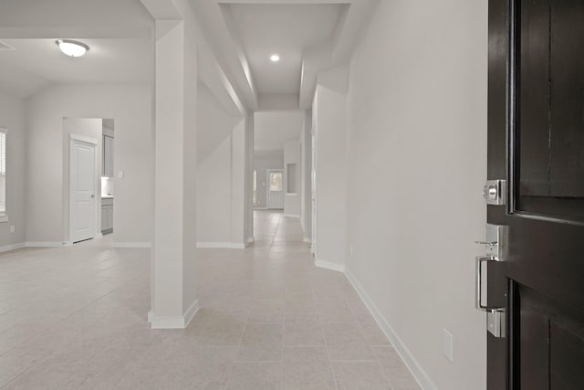 hall featuring light tile patterned flooring and vaulted ceiling