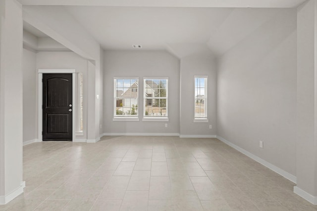 unfurnished room featuring vaulted ceiling and light tile patterned floors