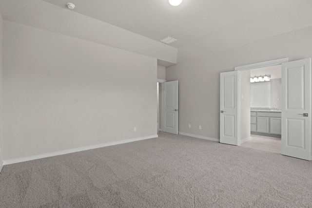 unfurnished bedroom featuring ensuite bath and light carpet