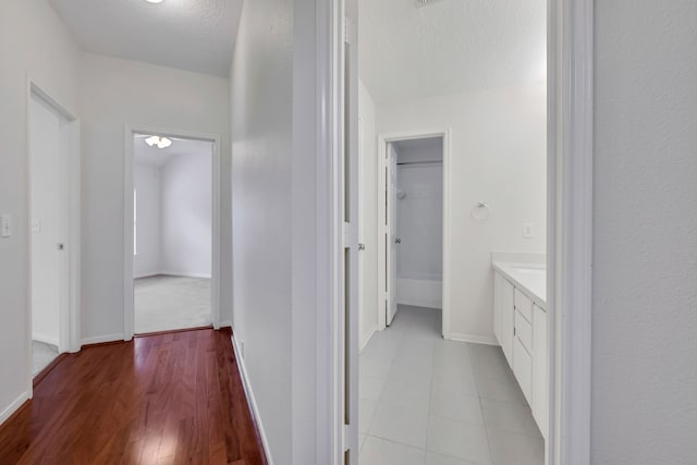 hall featuring light hardwood / wood-style flooring and a textured ceiling