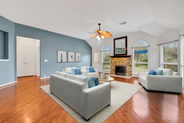 19110 Kelly Oaks Ct, Humble, TX 77346 - living room with a ceiling fan, visible vents, a fireplace with flush hearth, vaulted ceiling, and light wood-style flooring