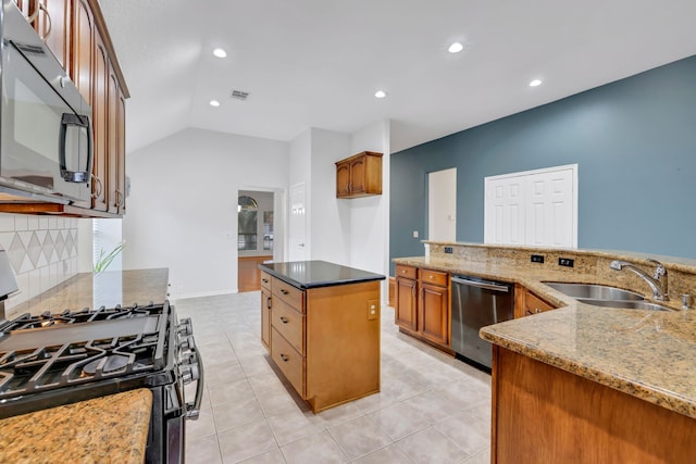 kitchen with vaulted ceiling, a kitchen island, appliances with stainless steel finishes, tasteful backsplash, and sink