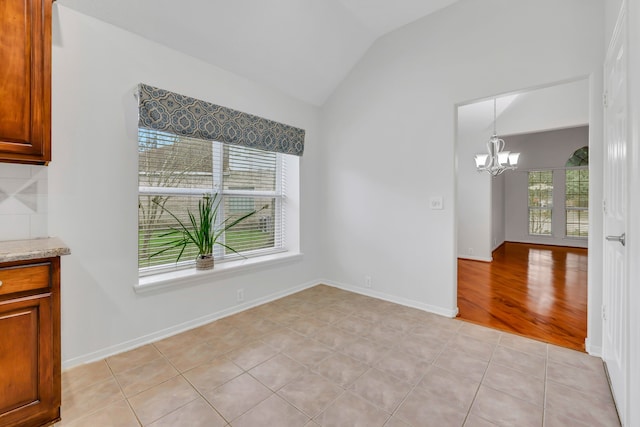 unfurnished dining area with vaulted ceiling, light tile patterned floors, and a chandelier