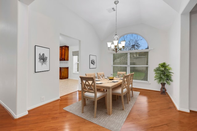 dining area featuring high vaulted ceiling, an inviting chandelier, and light wood-type flooring