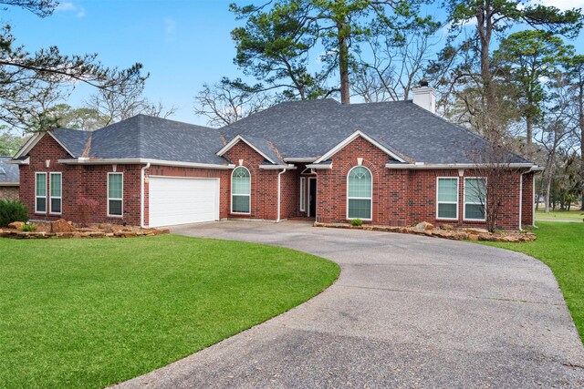 ranch-style house with driveway, a front lawn, a chimney, and brick siding