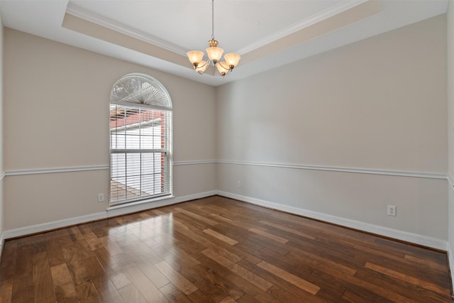 spare room with dark wood-style flooring, crown molding, a notable chandelier, a raised ceiling, and baseboards