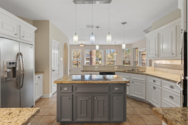 kitchen with white cabinets, a peninsula, black appliances, pendant lighting, and a sink