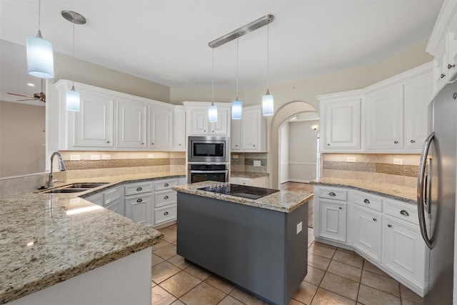 kitchen with stainless steel appliances, a sink, white cabinets, hanging light fixtures, and a center island