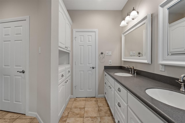 full bath with double vanity, baseboards, and a sink