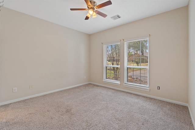 carpeted empty room with baseboards, visible vents, and a ceiling fan