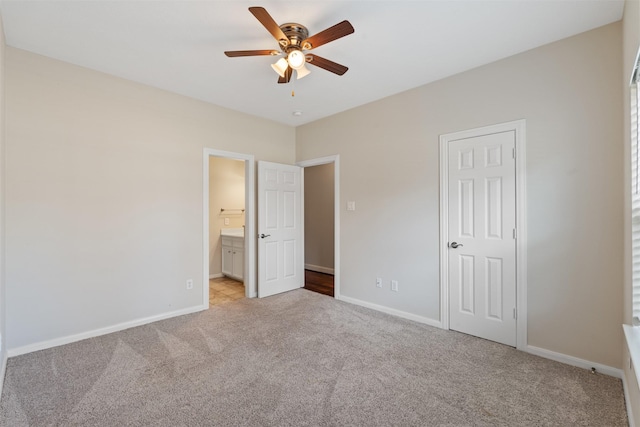 unfurnished bedroom with baseboards, ceiling fan, ensuite bathroom, and light colored carpet