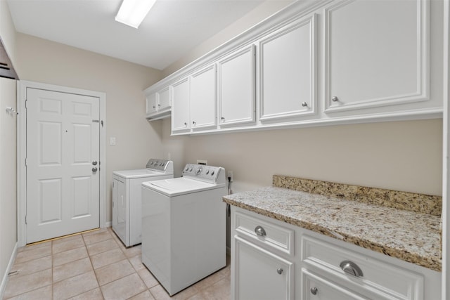 laundry room featuring cabinet space, light tile patterned floors, and washing machine and clothes dryer