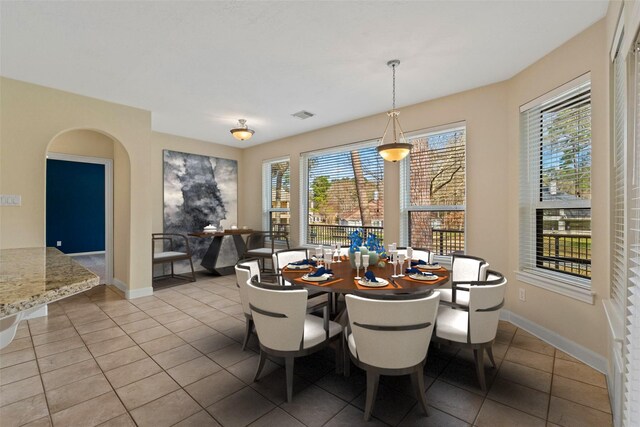 dining area featuring arched walkways, light tile patterned flooring, visible vents, and baseboards