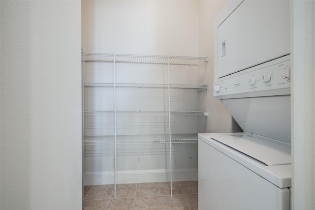 laundry area featuring stacked washer / drying machine and light tile patterned flooring