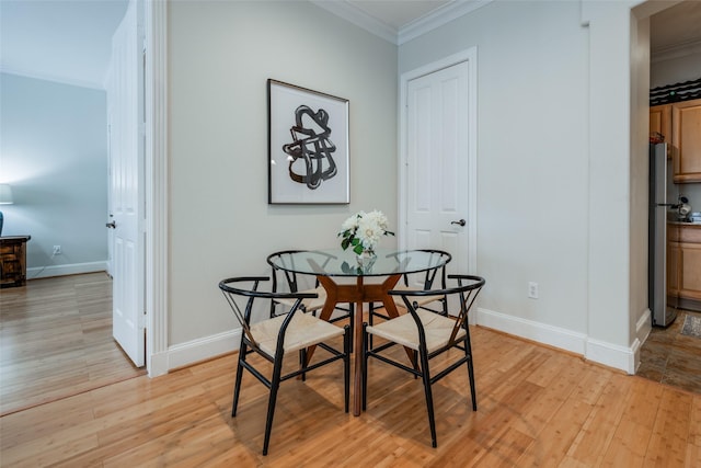 dining space with crown molding and light hardwood / wood-style flooring