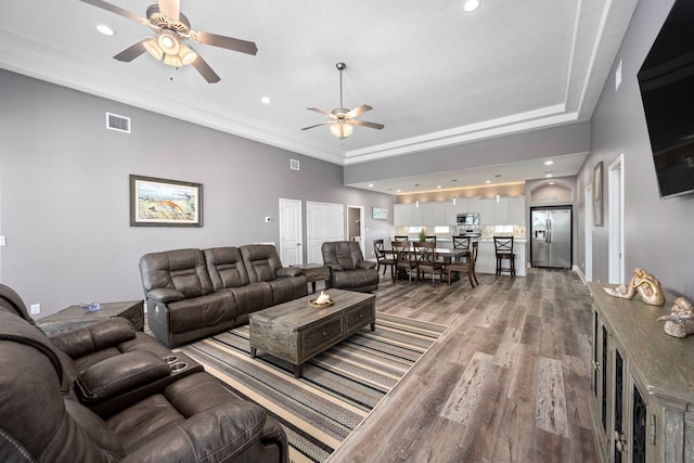 living room featuring wood-type flooring, ornamental molding, and ceiling fan