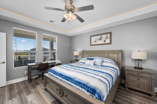 bedroom with dark wood-type flooring, a raised ceiling, and ceiling fan