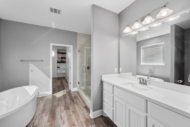 bathroom with hardwood / wood-style flooring, vanity, and plus walk in shower