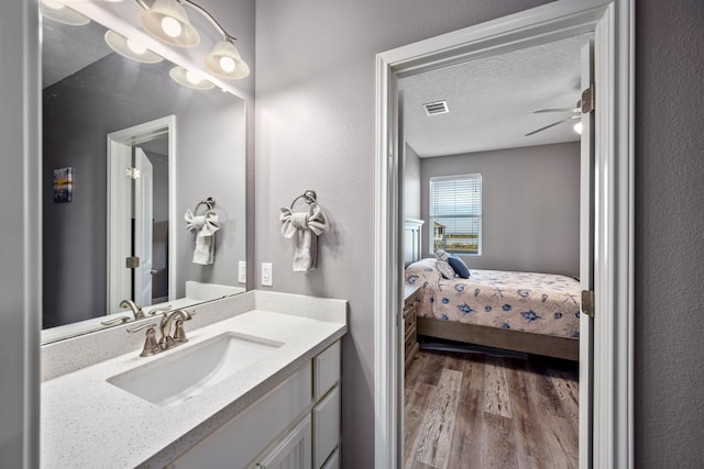 bathroom featuring wood-type flooring, ceiling fan, vanity, and a textured ceiling