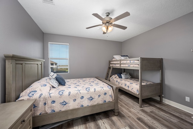 bedroom with a textured ceiling, wood-type flooring, and ceiling fan