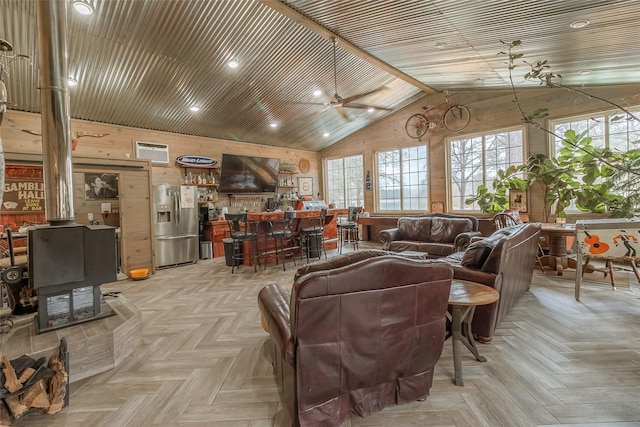 living room featuring lofted ceiling, wooden walls, light parquet floors, and a wood stove