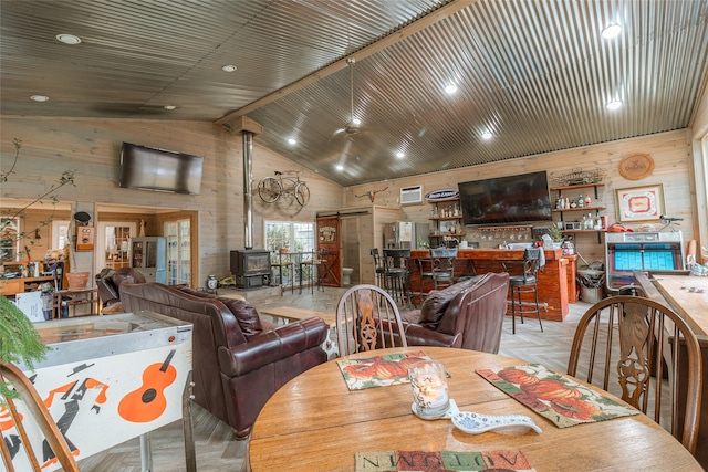 dining area with light parquet flooring, high vaulted ceiling, a wood stove, and wooden walls