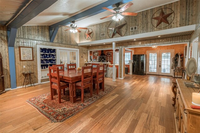 dining space featuring french doors, wood walls, high vaulted ceiling, beamed ceiling, and light hardwood / wood-style floors