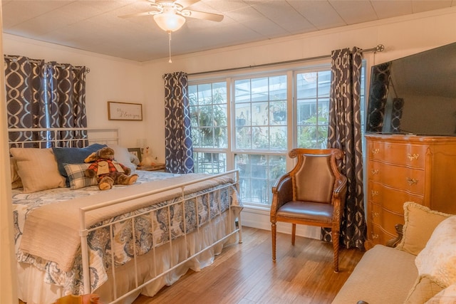 bedroom featuring wood-type flooring, ornamental molding, and ceiling fan