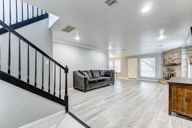 living room featuring crown molding, a fireplace, and light wood-type flooring