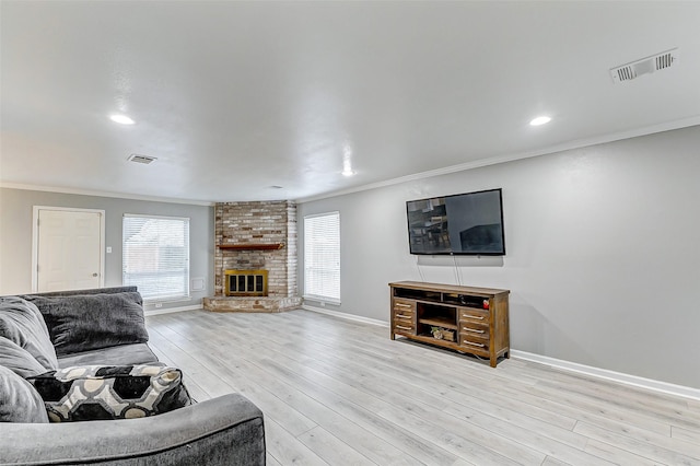 living room with ornamental molding, a brick fireplace, and light hardwood / wood-style floors