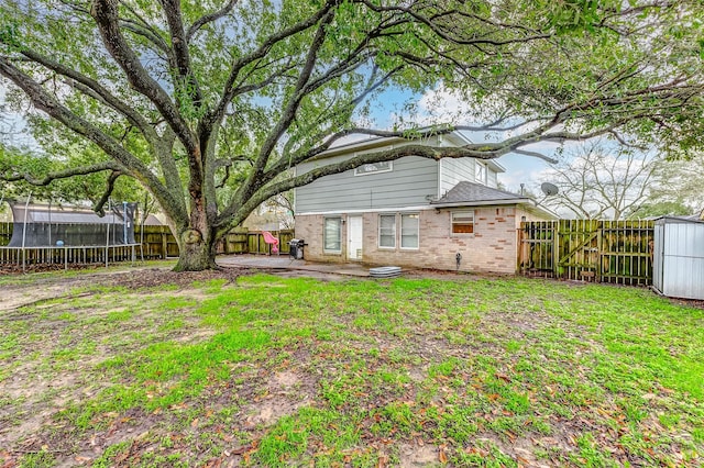 rear view of property with a trampoline, a lawn, and a patio