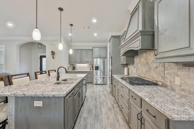 kitchen featuring sink, a kitchen breakfast bar, hanging light fixtures, stainless steel appliances, and a spacious island