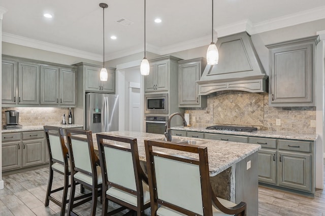 kitchen featuring a kitchen island with sink, sink, stainless steel appliances, and premium range hood