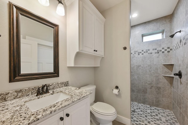 bathroom with vanity, a tile shower, and toilet