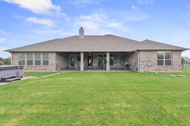 back of house featuring a hot tub, a patio, and a yard