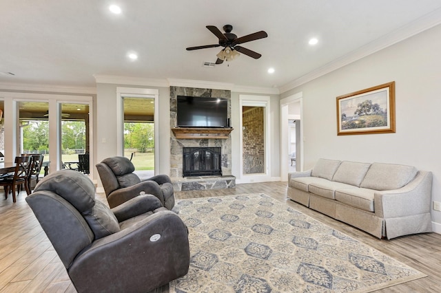 living room with ceiling fan, ornamental molding, a fireplace, and light hardwood / wood-style flooring