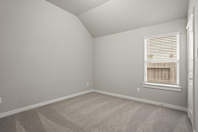 unfurnished room featuring lofted ceiling and carpet